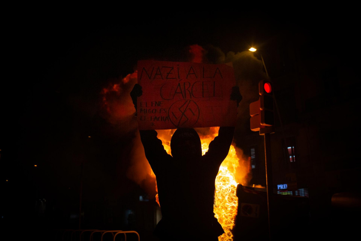 Uno de los manifestantes que apoyan a Pablo Hasel con una pancarta durante los disturbios en Barcelona el 17 de febrero
