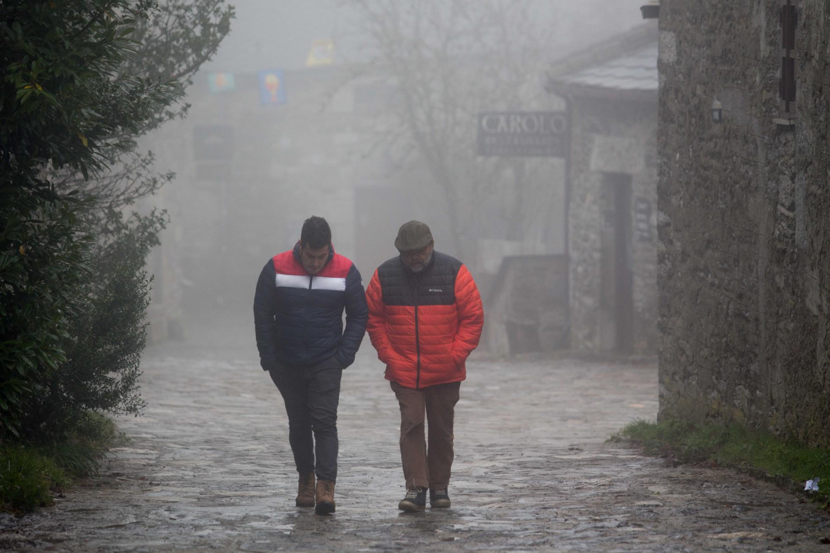 Dos hombres caminan entre la niebla en la aldea prerromana de O Cebreiro, Concello de Pedrafita do Cebreiro, Lugo, Galicia (España). A Montaña lucense ha registrado las primeras nevadas en las  zona
