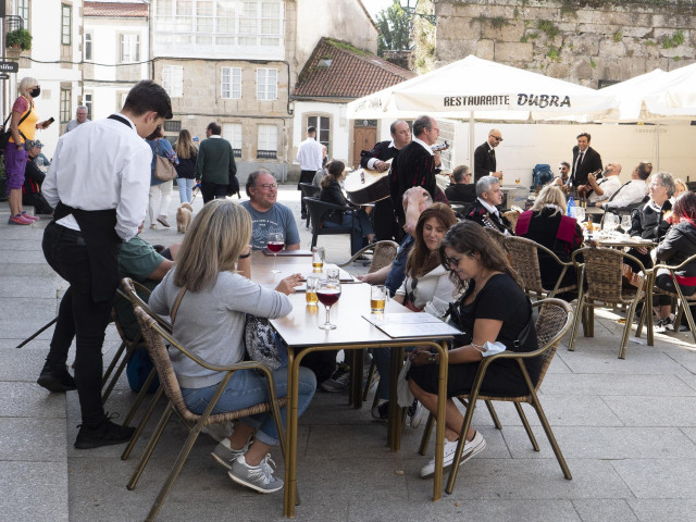 Archivo - Un grupo de turistas consulta una carta en la terraza de un bar en Santiago de Compostela.
