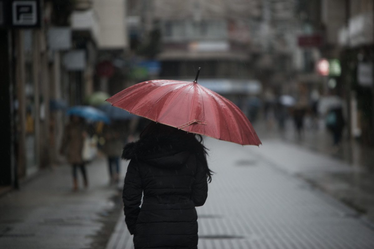 Una persona con paraguas para protegerse de la lluvia camina por la Rua Michelena, a 16 de enero de 2023, en Pontevedra.