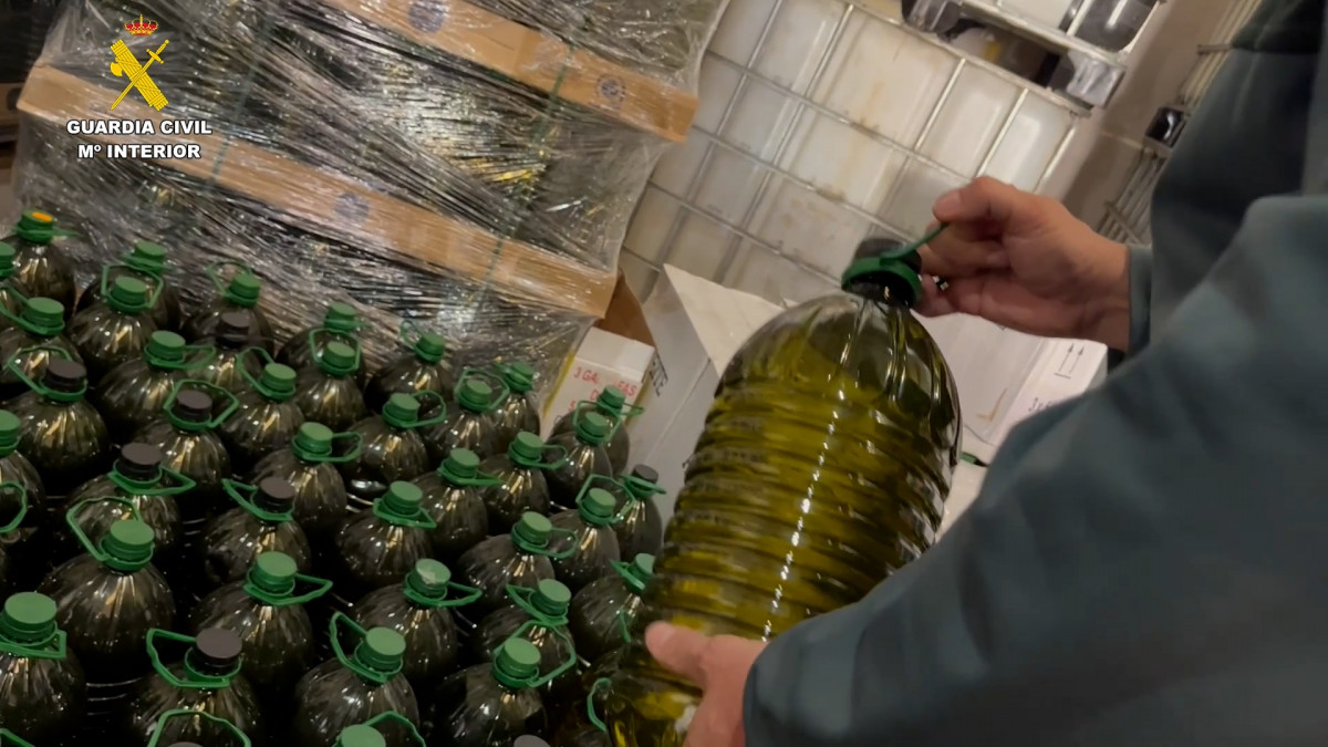 Agente de la Guardia Civil con las garrafas de aceite de oliva interceptadas durante la operación OPSON XII en España.