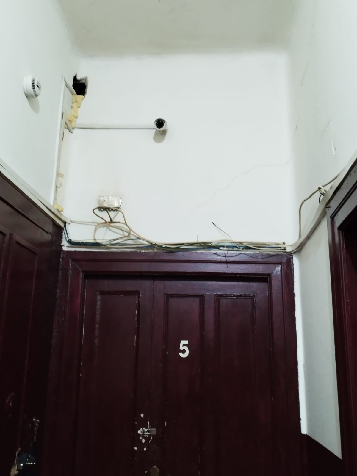 Puertas en Fisterra 11 con numeraciu00f3n y cables al aire en una foto facilitada por los inquilinos