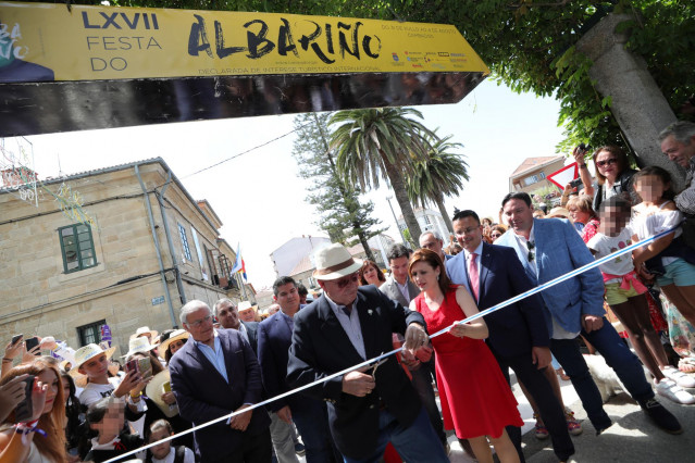 El pregonero de la LXVII Festa do Albariño en Cambados (Pontevedra), Salvador Cores ‘Manso’, junto a la alcaldesa de Cambados, Fátima Abal (con vestido rojo), corta la cinta blanca para inaugurar el evento.