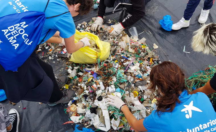 Voluntarios de la Caixa limpian de basura los arenales de Riazor y Orzán