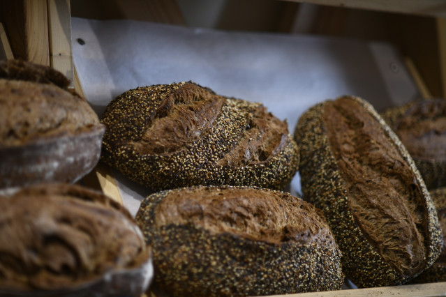 Unas hogazas de pan de semillas en el mostrador de una panadería.