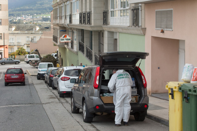 Un trabajador de Criminalística de la Guardia Civil en el maletero de su coche antes de entrar a la vivienda donde un menor de edad asesinó presuntamente a su madre la pasada noche del domingo al lunes, en el número 3 de la calle Costa do Castro, en la lo