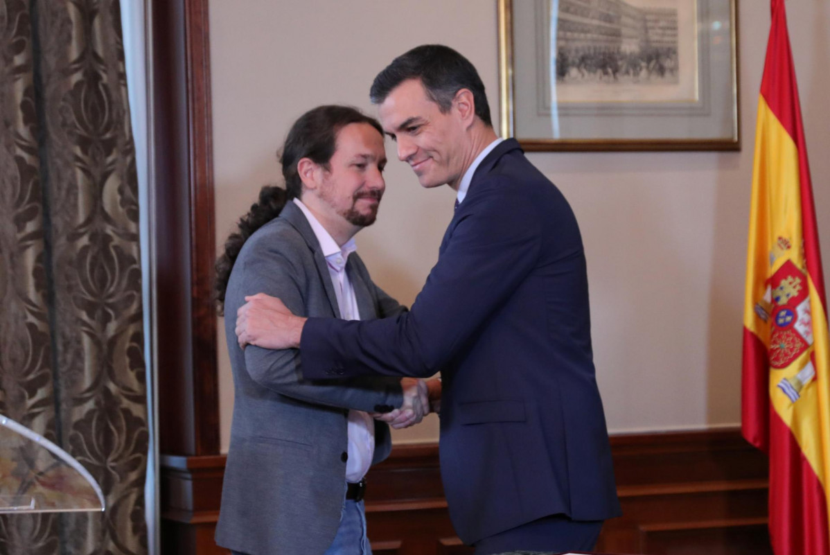 El presidente del Gobierno en funciones, Pedro Sánchez y el líder de Podemos, Pablo Iglesias, se abrazan en el Congreso de los Diputados después de firmar el principio de acuerdo para compartir un 