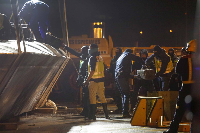 Agentes de la Policía y de la Guardia Civil descargan cocaína del narcosubmarino hundido el pasado fin de semana a la entrada de la ría de Aldán, en Cangas (Pontevedra) tras ser reflotado por dos grandes grúas