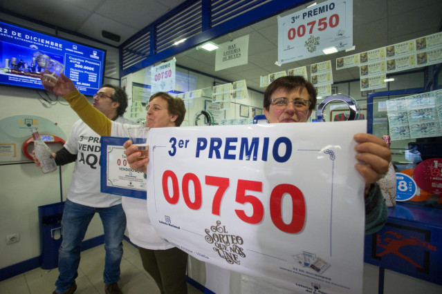 Los dueños del establecimento de lotería de Rua da Pravia, 18 de Vilalba, posan con el número 00750, premiado con el Tercer Premio del Sorteo Extraordinario de Lotería de Navidad 2019, el cual vendieron en su establecimiento, en Lugo /Galicia (España).
