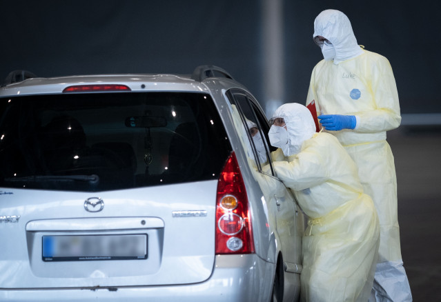 31 March 2020, Lower Saxony, Hanover: Doctors take a smear test from people inside their car at the newly installed Corona Drive-In test centre on the Hanover exhibition grounds. Photo: Peter Steffen/dpa