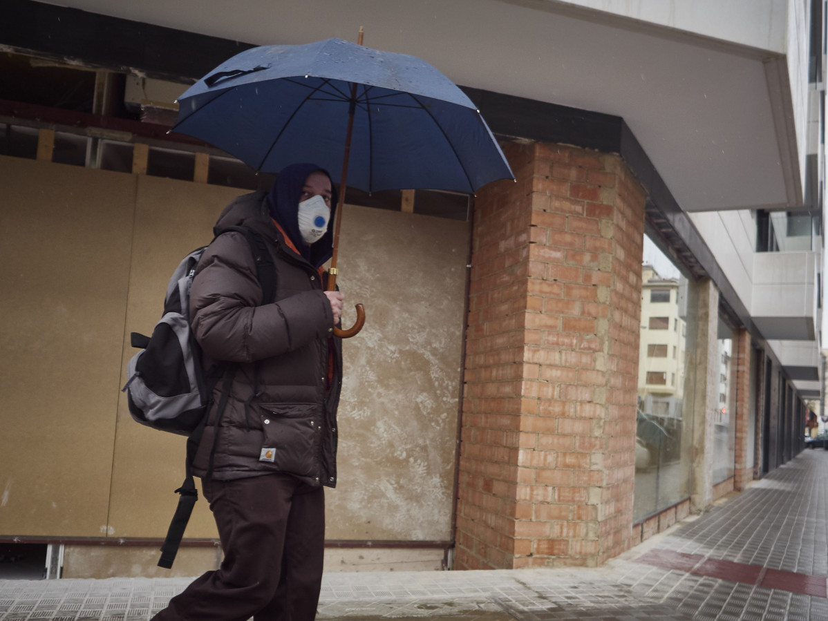 Un hombre con mascarilla camina protegiéndose con un paraguas por la lluvia  durante el Martes Santo y la cuarta semana del estado de alarma decretado por el Gobierno por la crisis del coronavirus, e