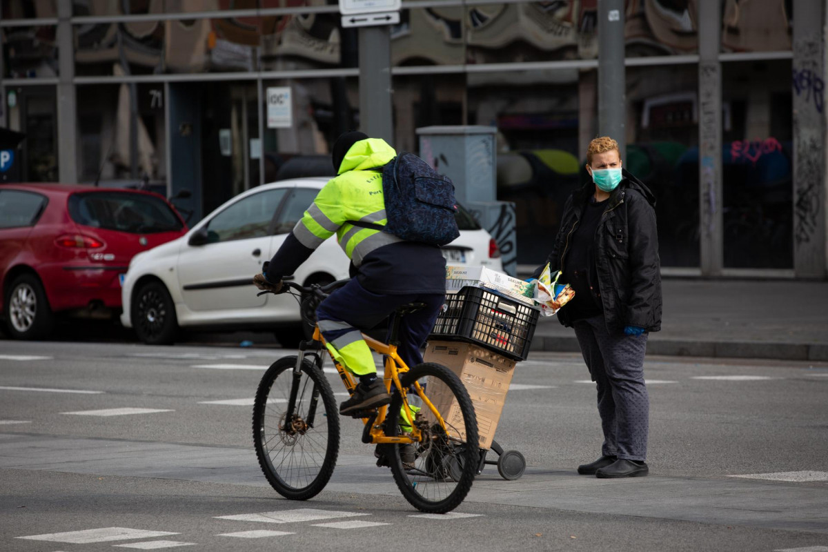 Un hombre que monta en bicicleta pasa junto a una mujer protegida con una mascarilla durante el noveno día laborable desde que se decretó el estado de alarma en el país a consecuencia del coronavirus, en Barcelona/Catalunya (España) a 26 de marzo de 2020.