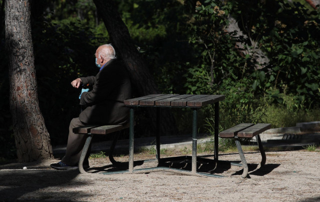 Un anciano con mascarilla descansa en el Parque Calero, en el distrito de Ciudad Lineal de la capital, uno de los que el Ayuntamiento de Madrid ha abierto y en los que se permite pasear y hacer ejercicio, en Madrid (España), a 8 de mayo de 20202.