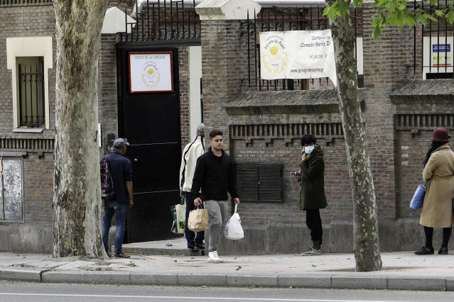 Decenas de personas esperan en la cola a las puertas del Comedor Social María Inmaculada de la capital para recoger alimentos y productos de primera necesidad en plena pandemia del Covid-19, durante el primer día en que los españoles pueden salir de casa