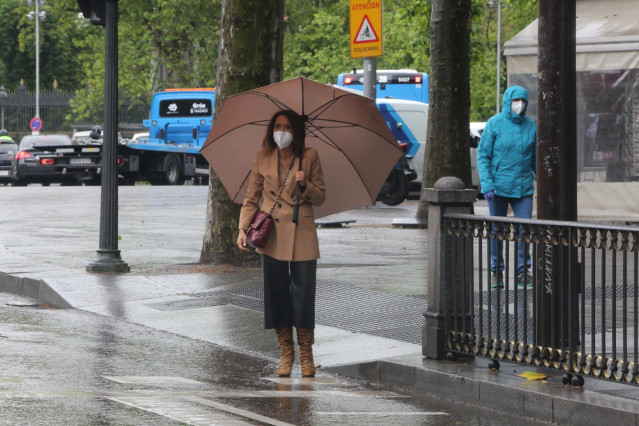 Una mujer con paraguas en Madrid en un día de lluvia y bajada de temperaturas en toda España, en que en gran parte de la Península y Baleares se espera nubosidad, con chubascos y tormentas casi generalizados, que podrán ser localmente fuertes o persistent