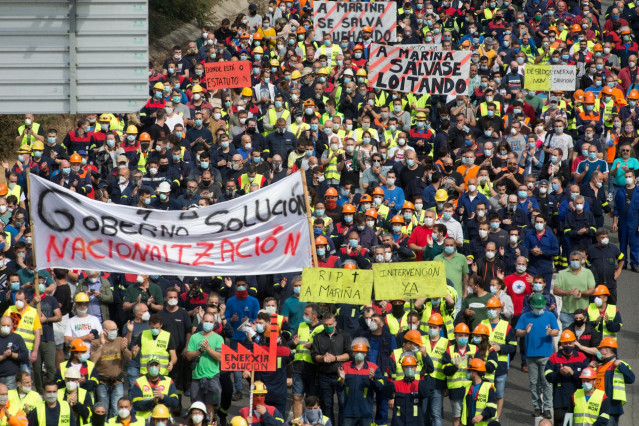 Participantes protegidos con mascarilla sujetan pancartas durante la manifestación del comité de empresa de Alcoa entre la factoría y la localidad de San Cibrao, a 2 de junio de 2020.