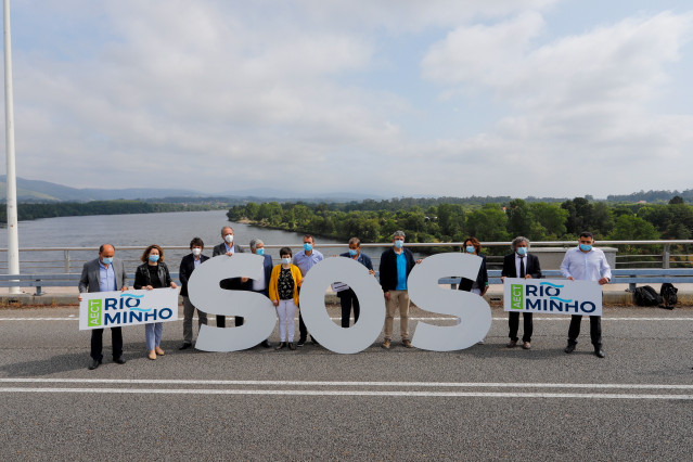 doce concellos del Miño en la provincia de Pontevedra y del norte de Portugal sostienen varias pancartas en la protesta simbólica conjunta en el Puente de la Amistad, que une la localidad pontevedresa de Tomiño y la portuguesa Vilanova da Cerveira.