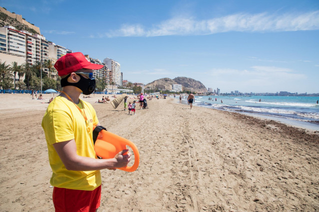 Un socorrista protegido con mascarilla vigila la Playa del Postiguet durante el primer día de la Fase 2, cuando se puede acceder a las playas de la misma provincia, isla o unidad territorial de referencia establecida en el plan de desescalada, y cuando lo