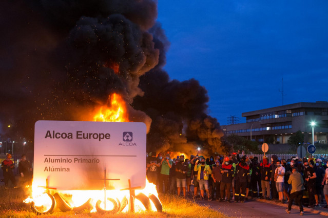 Manifestantes durante una concentración nocturna convocada por el comité de Alcoa San Cibrao, en el entorno de la fábrica de San Cibrao, queman el cartel de la multinacional en Lugo, Galicia (España), a 30 de junio