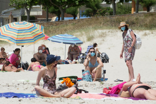 Varias personas protegidas con mascarillas toman el sol en la Playa de A Rapadoira en Foz, en la comarca de A Mariña, Lugo, Galicia (España), a 9 de julio de 2020. El pasado 5 de julio la Xunta ordenó el cierre hasta mañana 10 de julio de los accesos del