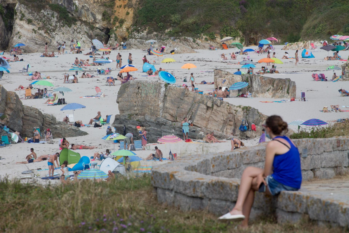 Una persona sentada frente a la playa en A Mariña (Lugo/Galicia) a 27 de julio de 2020. La comarca mantiene este domingo 51 casos activos de COVID-19 tras una nueva alta y un nuevo contagio con respe