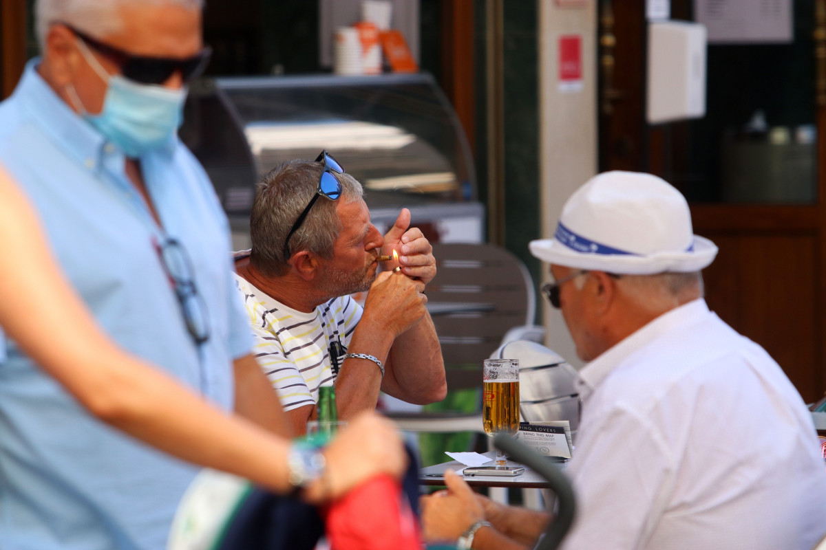 Personas fumando en terrazas y vías públicas  durante el día en el que se ha decretado la prohibición de fumar en espacios públicos si no se respeta la distancia de seguridad establecida. Málaga