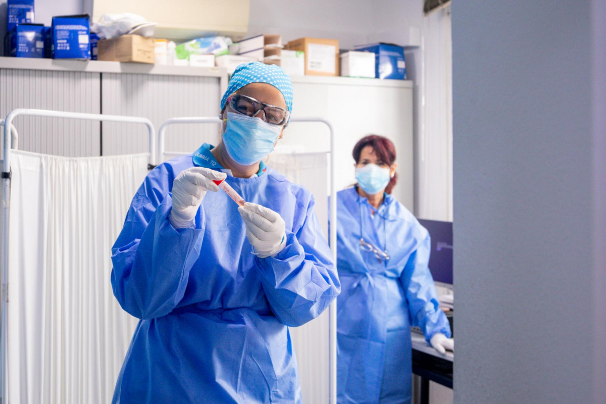 Un trabajador sanitario protegido sostiene una de las probetas utilizadas para la realización de tests PCR .