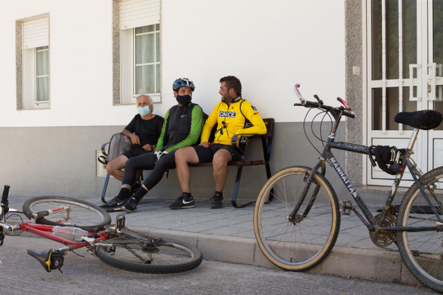 Los hermanos Primi (d) y Mario (c) y su tío Pedro (i), descansan junto a sus bicicletas en un banco de la localidad de Triacastela, fin de su etapa diaria, mientras los peregrinos retornan al Camino francés de la Ruta Jacobea casi un mes después del fin d