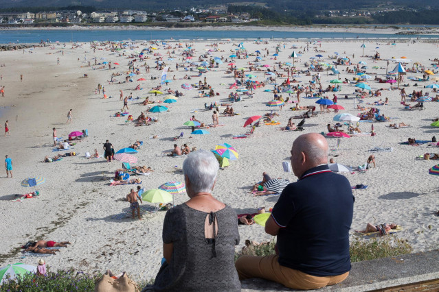 Dos personas observan la playa en A Mariña (Lugo/Galicia) a 27 de julio de 2020