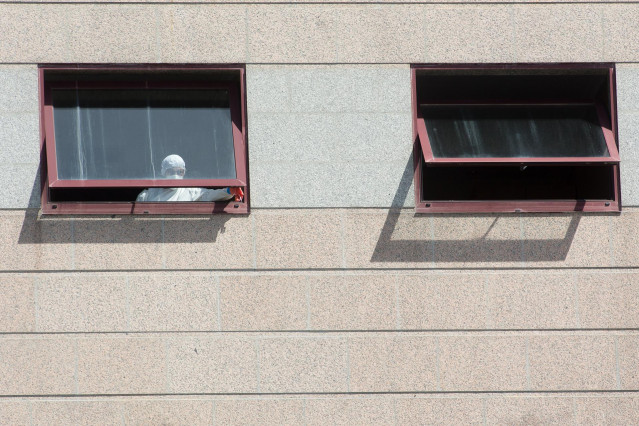 Un trabajador protegido es visto por uno de los cristales de la residencia de mayores DomusVi de Outeiro de Rei en Lugo, Galicia (España), a 8 de septiembre de 2020. La Xunta ha intervenido el geriátrico tras detectar 99 positivos más en covid-19, 94 de e