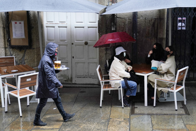 Una camarera lleva varias cervezas a una de las mesas de la terraza de su establecimiento, en Santiago de Compostela, A Coruña (Galicia),