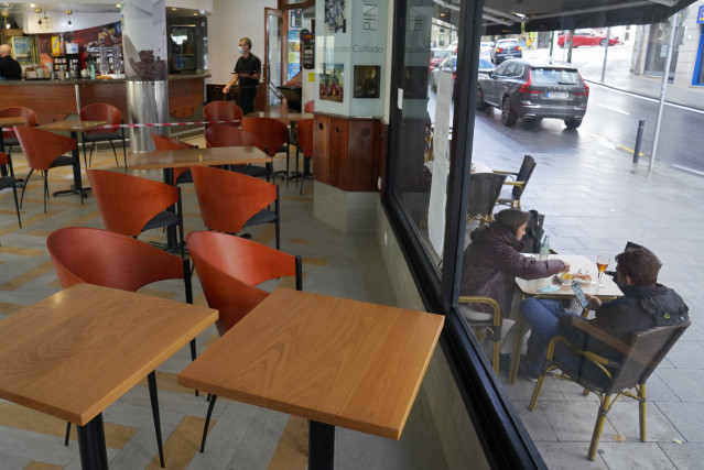 Dos personas toman el aperitivo en una mesa de la terraza de un bar, en Santiago de Compostela, A Coruña (Galicia), a 22 de octubre de 2020. Galicia ha entrado a las 00,00 horas de este jueves, en nivel 2 por el que se limitan en toda la Comunidad gallega