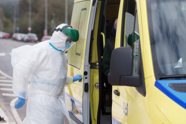 Un trabajador sanitario totalmente protegido cierra la puerta de una ambulancia tras recoger a un anciano de la residencia de ancianos de San Cibrao.