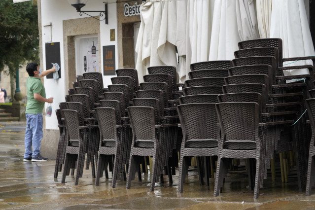 Un trabajador limpia la pizarra de un establecimiento cerrado durante el primer día de cierre en la hostelería decretado debido a la crisis del Covid-19, en Santiago de Compostela, Galicia, (España), a 7 de noviembre.