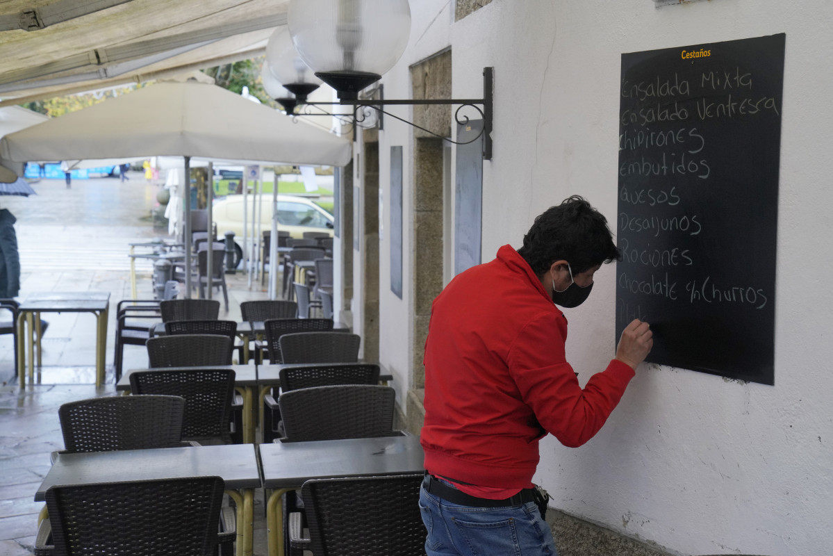 Un hombre escribe en la pizarra de un mesón, en Santiago de Compostela, A Coruña, Galicia (España), a 4 de diciembre de 2020. Hoy se reabre la hostelería en toda Galicia, aunque en distinto grado 