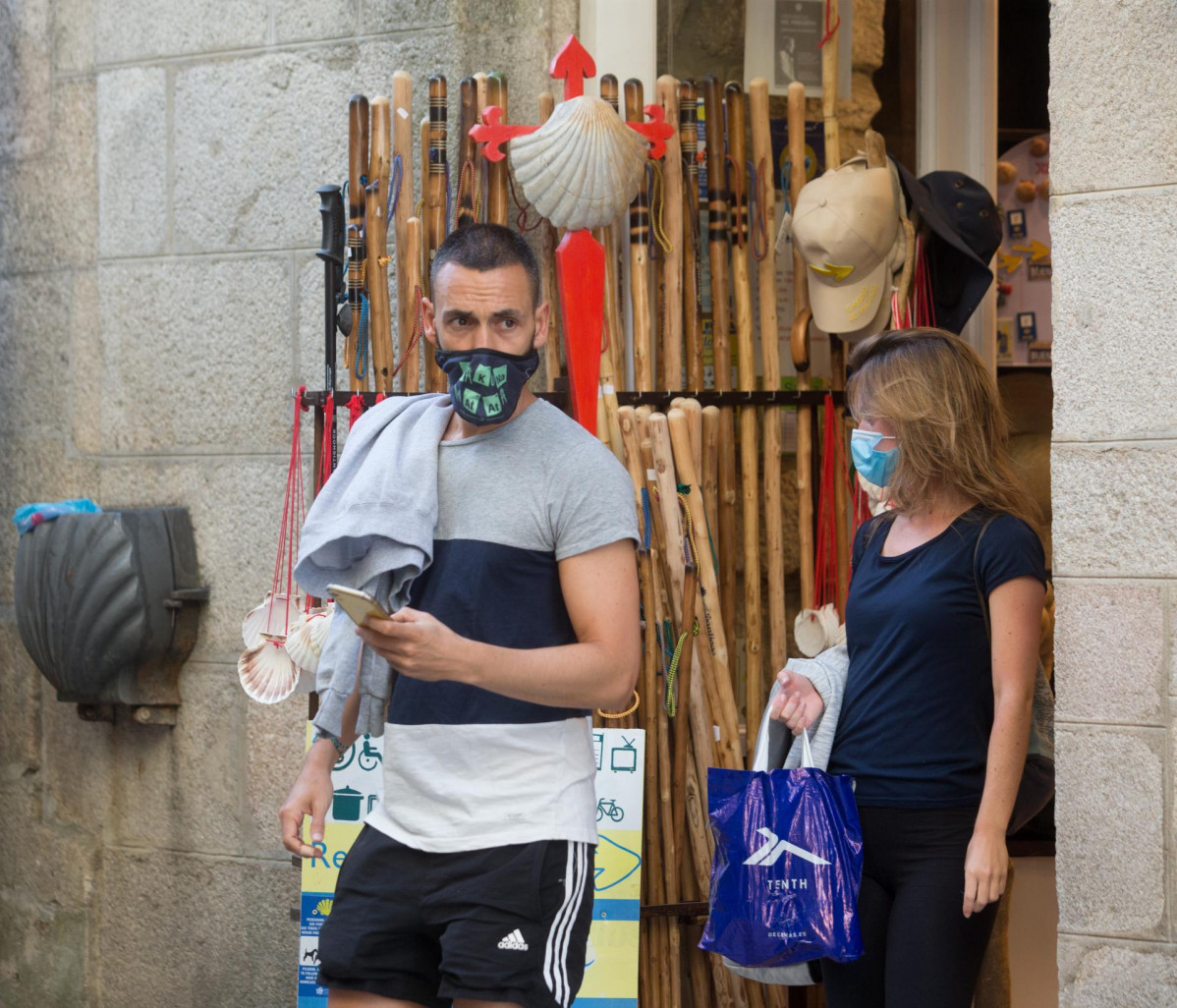 Los peregrinos alicantinos Miguel Ángel y Elena salen de un establecimiento con elementos del Camino a la venta en la localidad de Sarria, mientras los peregrinos retornan al Camino francés de la Ru