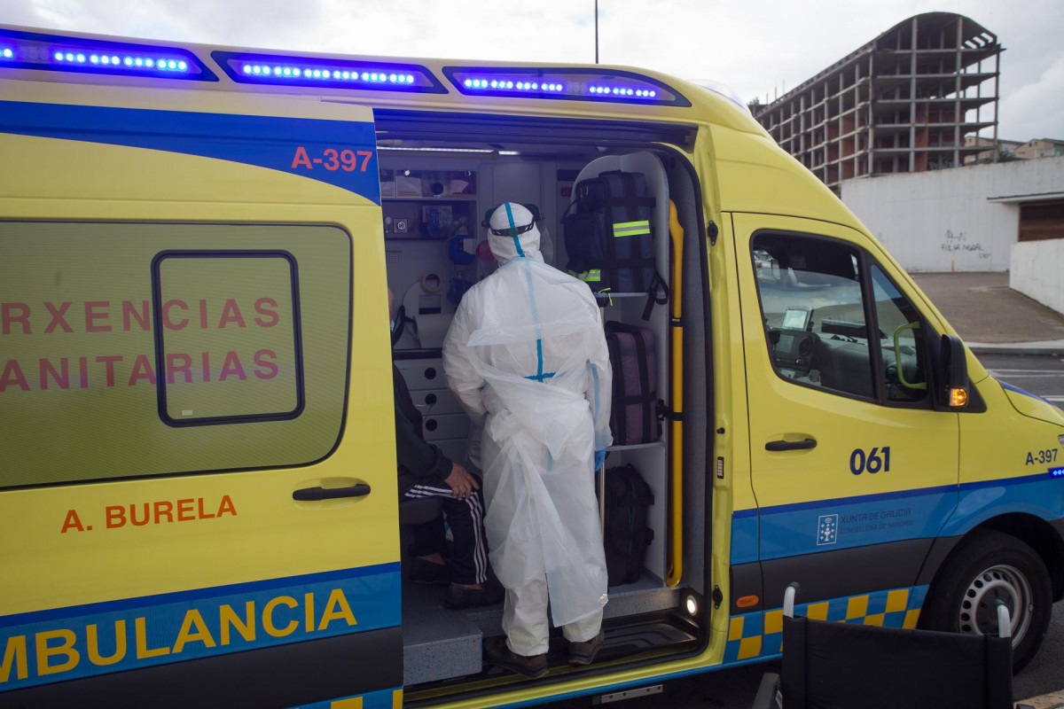 Un trabajador sanitario totalmente protegido ayuda a subir a la ambulancia a un anciano de la residencia de ancianos de San Cibrao donde se ha originado un brote de Covid-19, en San Cibrao, Lugo, Gali