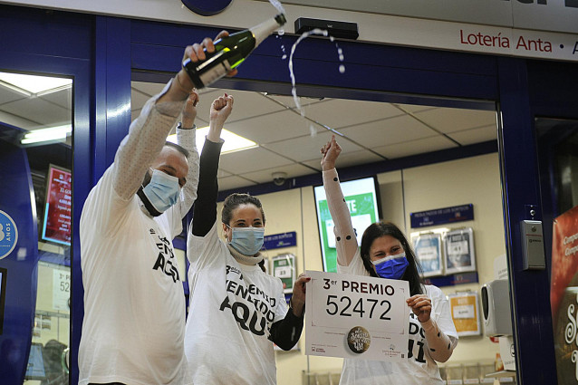 Tres loteros celebran con champán y posan con el Tercer premio en la administración de lotería situada en calle del Paseo, en Ourense.