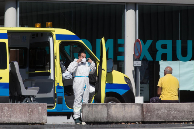 Un profesional sanitario baja de la ambulancia en la que viaja un paciente con Covid-19