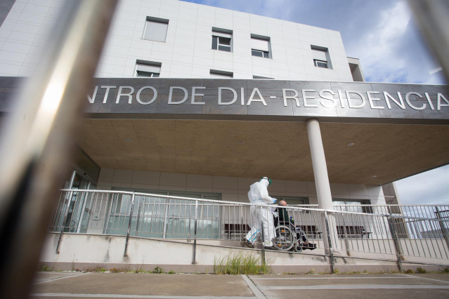 Un trabajador sanitario totalmente protegido acuden a buscar a un anciano de la residencia de ancianos de San Cibrao donde se ha originado un brote de Covid-19, en San Cibrao, Lugo, Galicia, (España), a 9 de noviembre de 2020. En el centro la situación ac