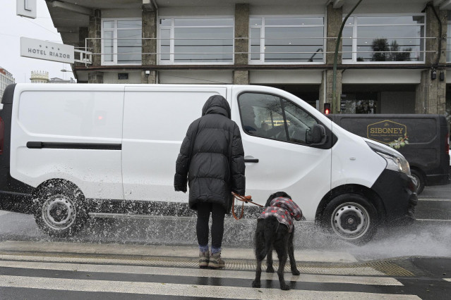 Una mujer espera con su perro antes de cruzar por un paso de cebra de A Coruña, Galicia (España)