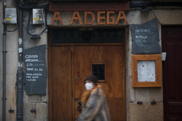 Una mujer con mascarilla pasa por delante de un restaurante el primer día del cierre perimetral decretado en Lugo, Galicia (España), a 15 de enero de 2021. El cierre perimetral forma parte del paquete de nuevas restricciones de la Xunta para frenar la exp