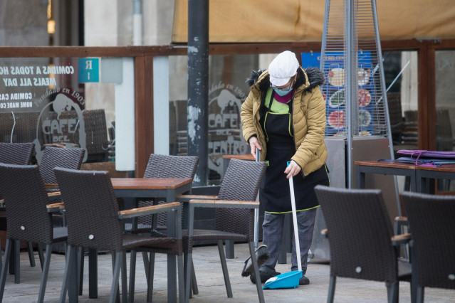 Una mujer barre la terraza de un restaurante el primer día del cierre perimetral decretado en Lugo, Galicia (España), a 15 de enero de 2021.
