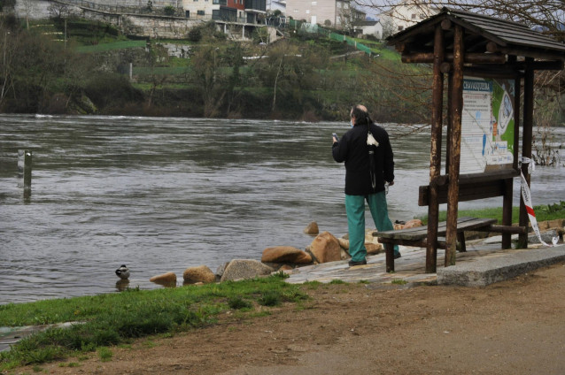 Una persona realiza una fotografía al río Miño que ha inundado la zona del paseo de O Tinteiro y la zona termal a Chavasqueira de Ourense, Galicia (España), a 11 de febrero de 2021
