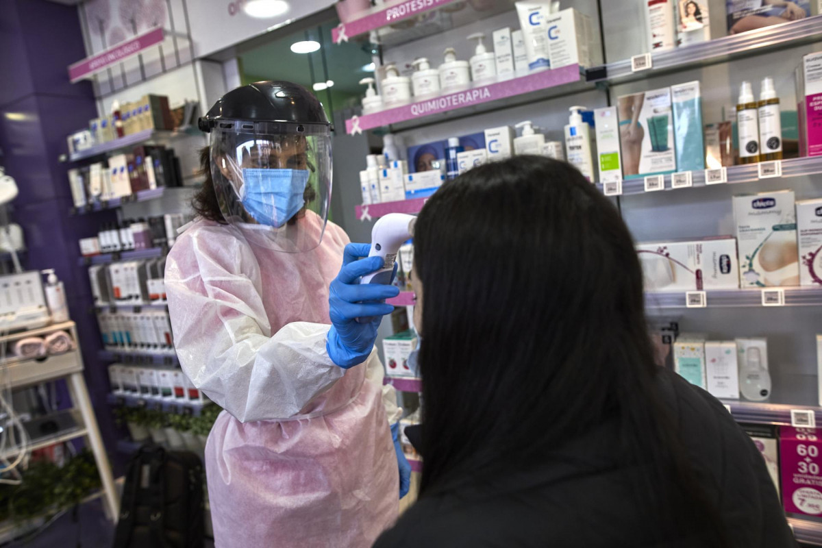 Una farmacéutica toma la temperatura a una mujer antes de realizarle un test de antígenos en la Farmacia Las Gemelas en Madrid (España), a 11 de febrero de 2021. El pasado miércoles 3 de febrero, 
