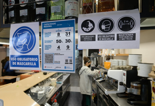 Varios carteles donde se muestra el aforo y el código QR en la puerta de un restaurante en A Coruña a 12 de marzo de 2021