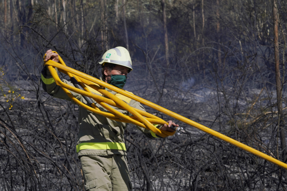 Un bombero apaga el incendio forestal en la parroquia de Figueriras en Santiago de Compostela, A Coruña, Galicia (España), a 20 de marzo de 2021. El incendio, ya estabilizado, se originó en torno a