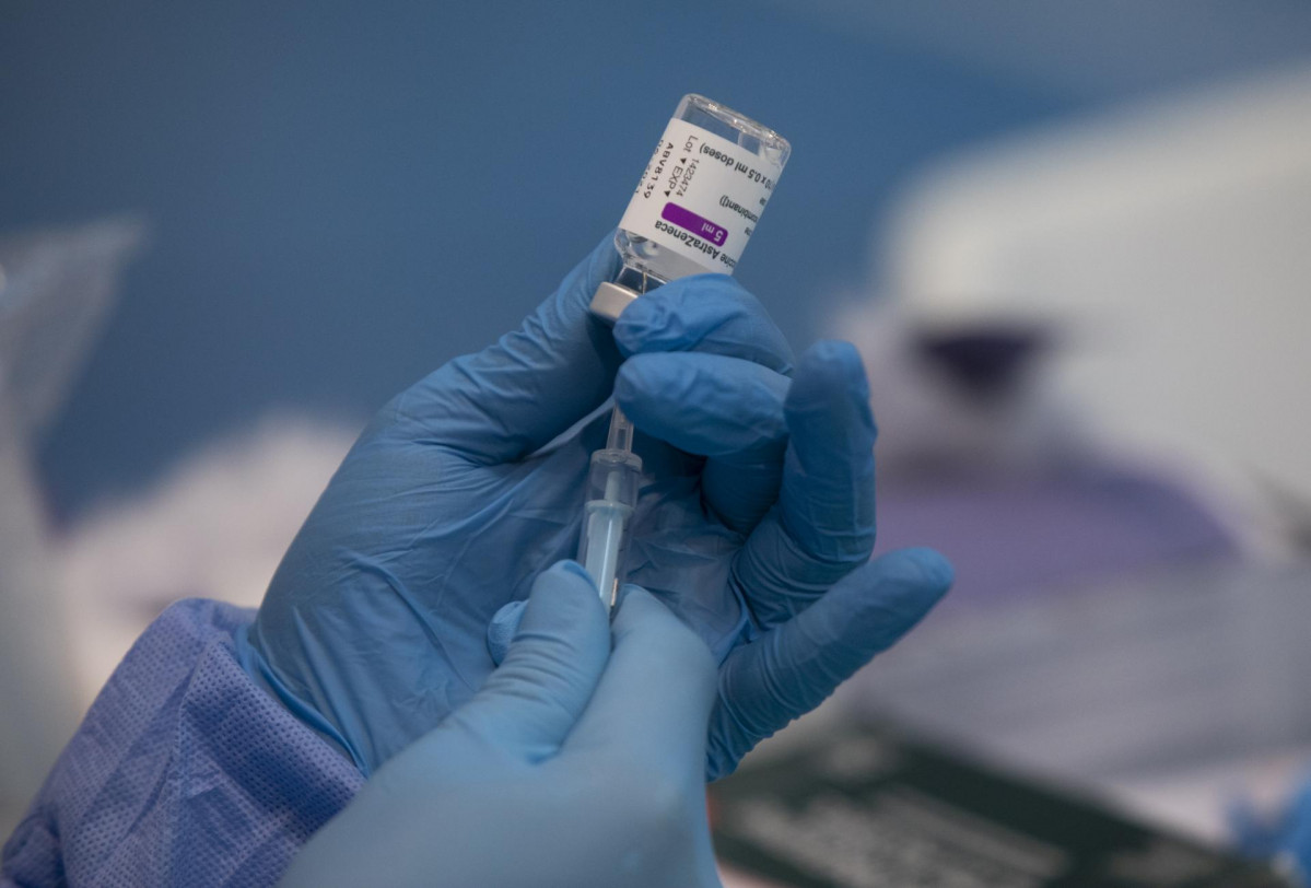 Una profesional sanitaria sostiene una jeringuilla con un vial de la vacuna contra la COVID-19 de AstraZeneca en un dispositivo de vacunación en el pabellón SADUS en Sevilla (Andalucía, España), a