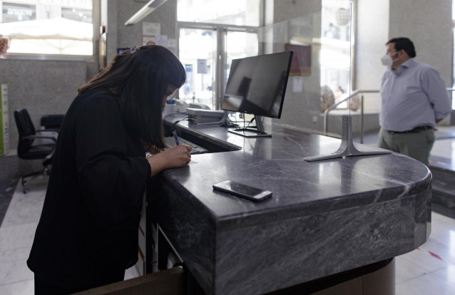 Archivo - Una trabajadora en la recepción de un hotel atiende a un viajero