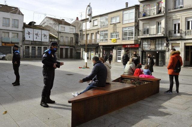 Archivo - Agentes de la Policía Local de Xinzo de Limia y vecinos en la plaza Mayor adornada con el 
